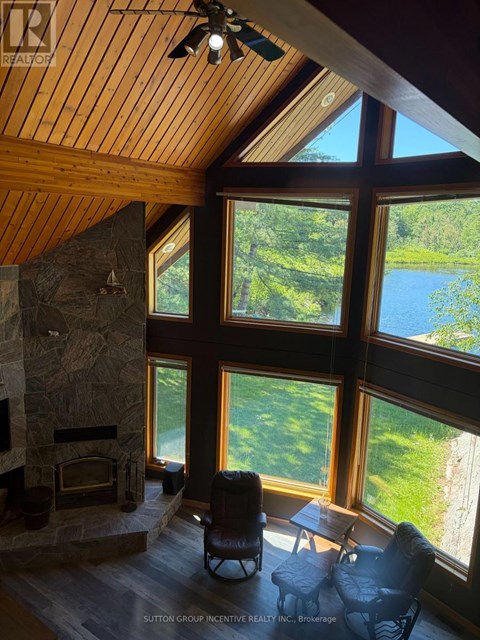 A living room with a stone fireplace and a view of a lake.