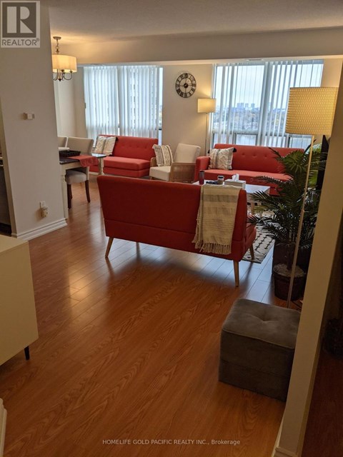 A living room with a red couch and a wooden floor.