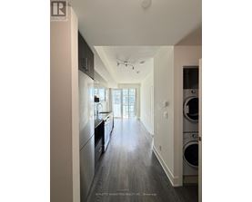 A modern kitchen with dark wood floors and stainless steel appliances.