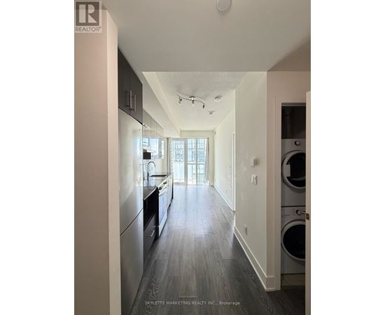 A modern kitchen with dark wood floors and stainless steel appliances.
