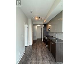 A modern kitchen with dark wood floors and white walls.