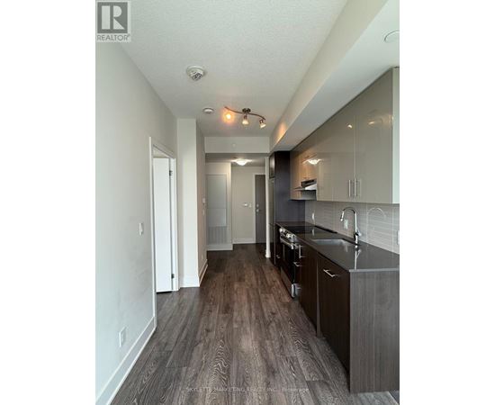 A modern kitchen with dark wood floors and white walls.