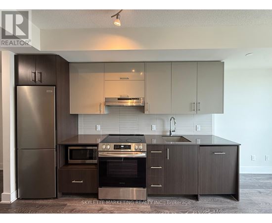 A modern kitchen with dark wood cabinets and stainless steel appliances.
