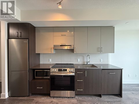 A modern kitchen with dark wood cabinets and stainless steel appliances.