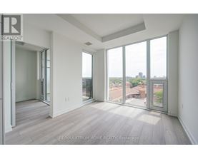 A spacious room with a view of the cityscape through large windows.
