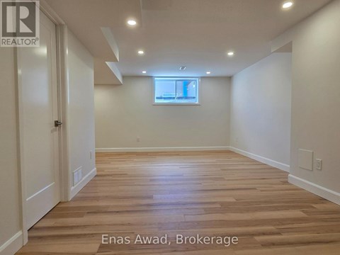 A spacious room with wooden flooring and white walls.