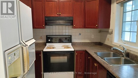 A kitchen with a refrigerator, oven, and sink.