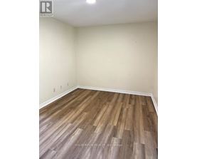 A room with wooden flooring and a white wall.
