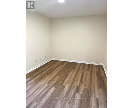 A room with wooden flooring and a white wall.