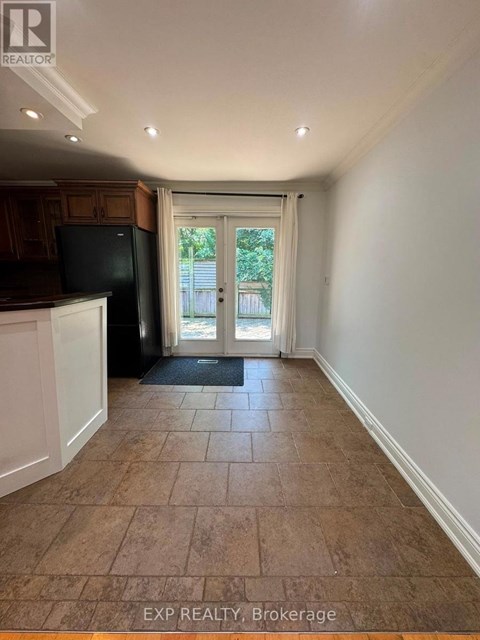 A kitchen area with a black fridge and a doorway leading outside.