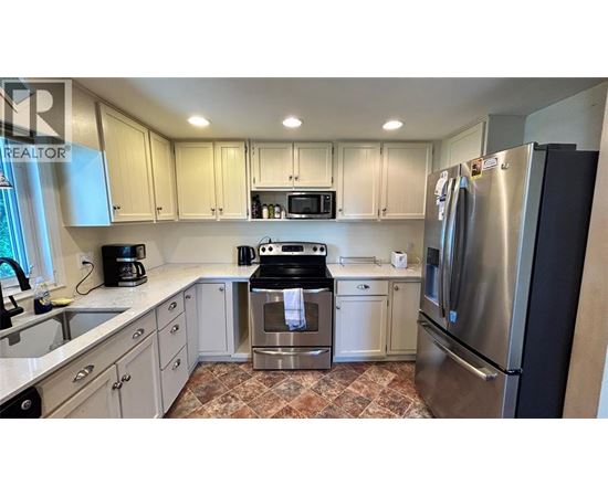 A kitchen with a refrigerator, oven, and microwave.