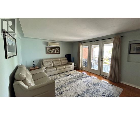 A living room with a beige couch and a blue rug.