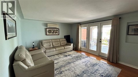 A living room with a beige couch and a blue rug.
