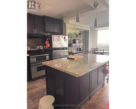 A kitchen with a marble counter top and black cabinets.
