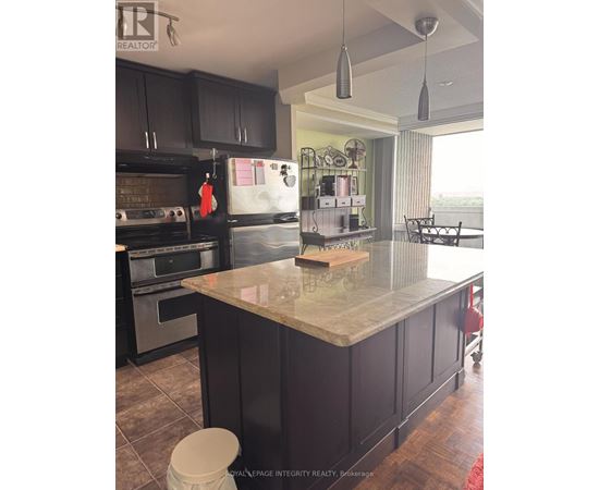 A kitchen with a marble counter top and black cabinets.