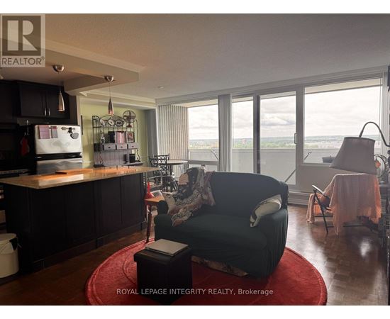 A living room with a black couch and a red rug.