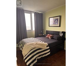 A bedroom with a bed covered in a striped comforter.