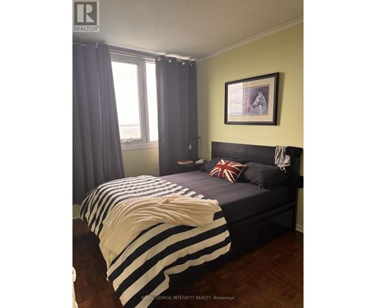 A bedroom with a bed covered in a striped comforter.