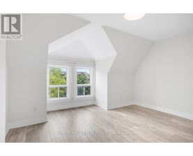 A spacious room with a large window and wooden flooring.