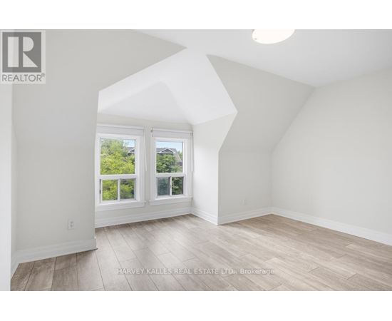 A spacious room with a large window and wooden flooring.