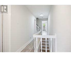 A hallway with a staircase leading to a door.