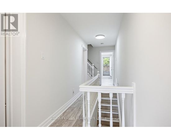 A hallway with a staircase leading to a door.