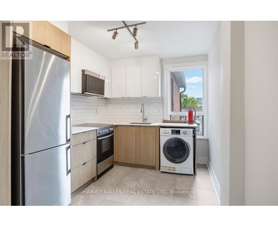 A kitchen with a refrigerator, oven, and washing machine.