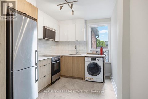 A kitchen with a refrigerator, oven, and washing machine.