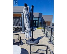 A patio with a table, chairs and a black umbrella.
