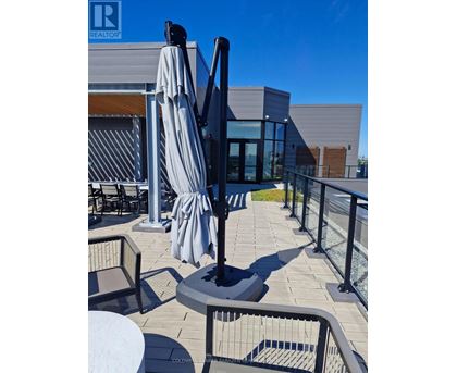 A patio with a table, chairs and a black umbrella.