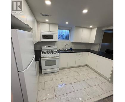 A kitchen with white appliances and black countertops.