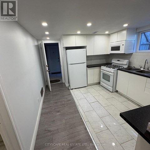 A kitchen with white cabinets and a black countertop.