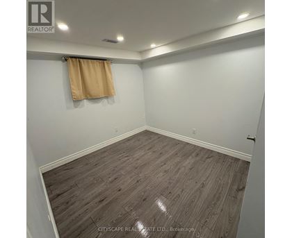 A room with wooden flooring and a tan curtain.