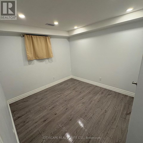 A room with wooden flooring and a tan curtain.