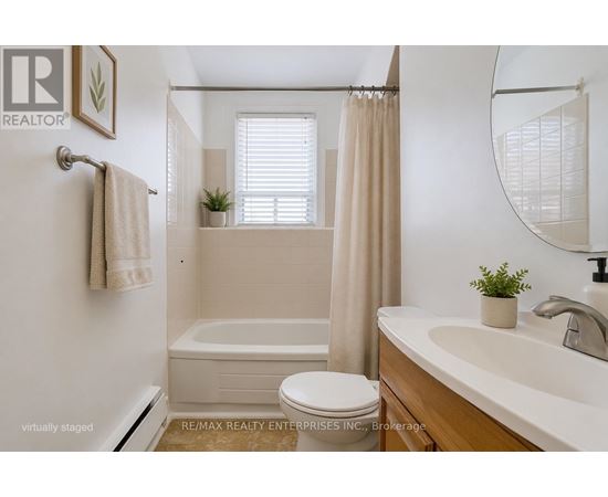 A white bathroom with a towel hanging on the door.