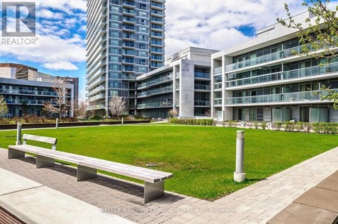 A park with benches and a grassy area in front of apartment buildings.