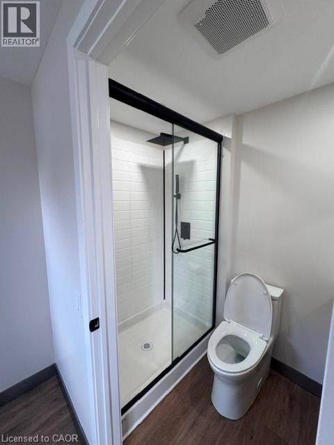 A white toilet in a small bathroom with a walk-in shower.