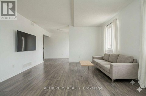 A living room with a couch, a television, and a window.