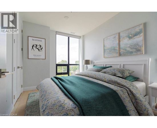 A bedroom with a bed covered in a green comforter and a painting on the wall.