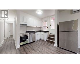 A real estate listing image of a kitchen with white cabinets and stainless steel appliances.