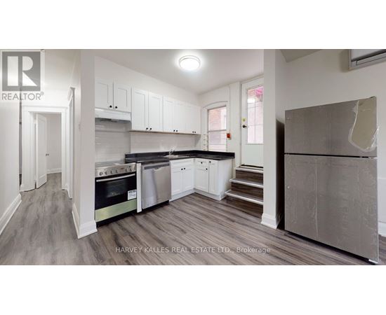 A real estate listing image of a kitchen with white cabinets and stainless steel appliances.