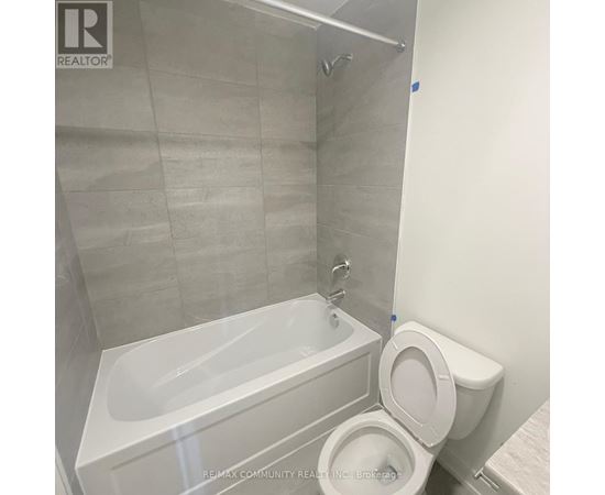 A white toilet sits next to a white bathtub in a bathroom.