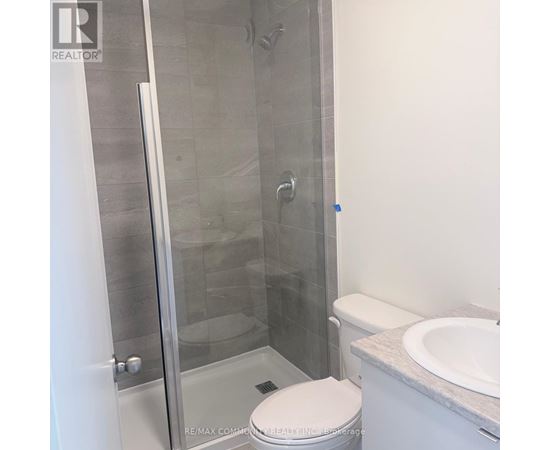 A white toilet sits next to a walk-in shower.