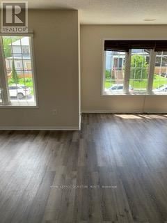 A room with a wooden floor and a window showing a parking lot outside.