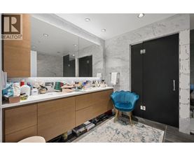 A bathroom with a blue chair and a marble wall.