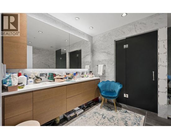 A bathroom with a blue chair and a marble wall.
