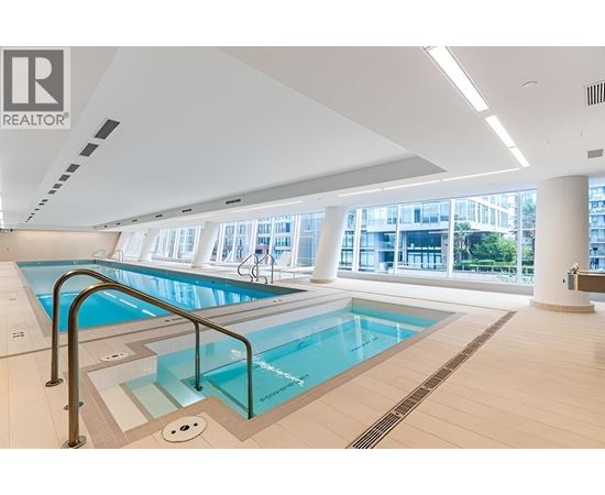 A large indoor swimming pool with a glass barrier.