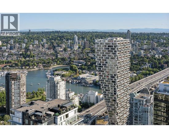 A cityscape with a tall building in the foreground and a body of water in the middle ground.