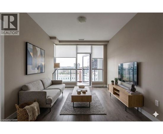 A living room with a grey couch, a coffee table, and a large window.