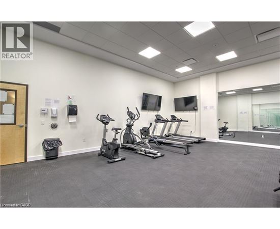 A gym with treadmills, exercise bikes, and a television.